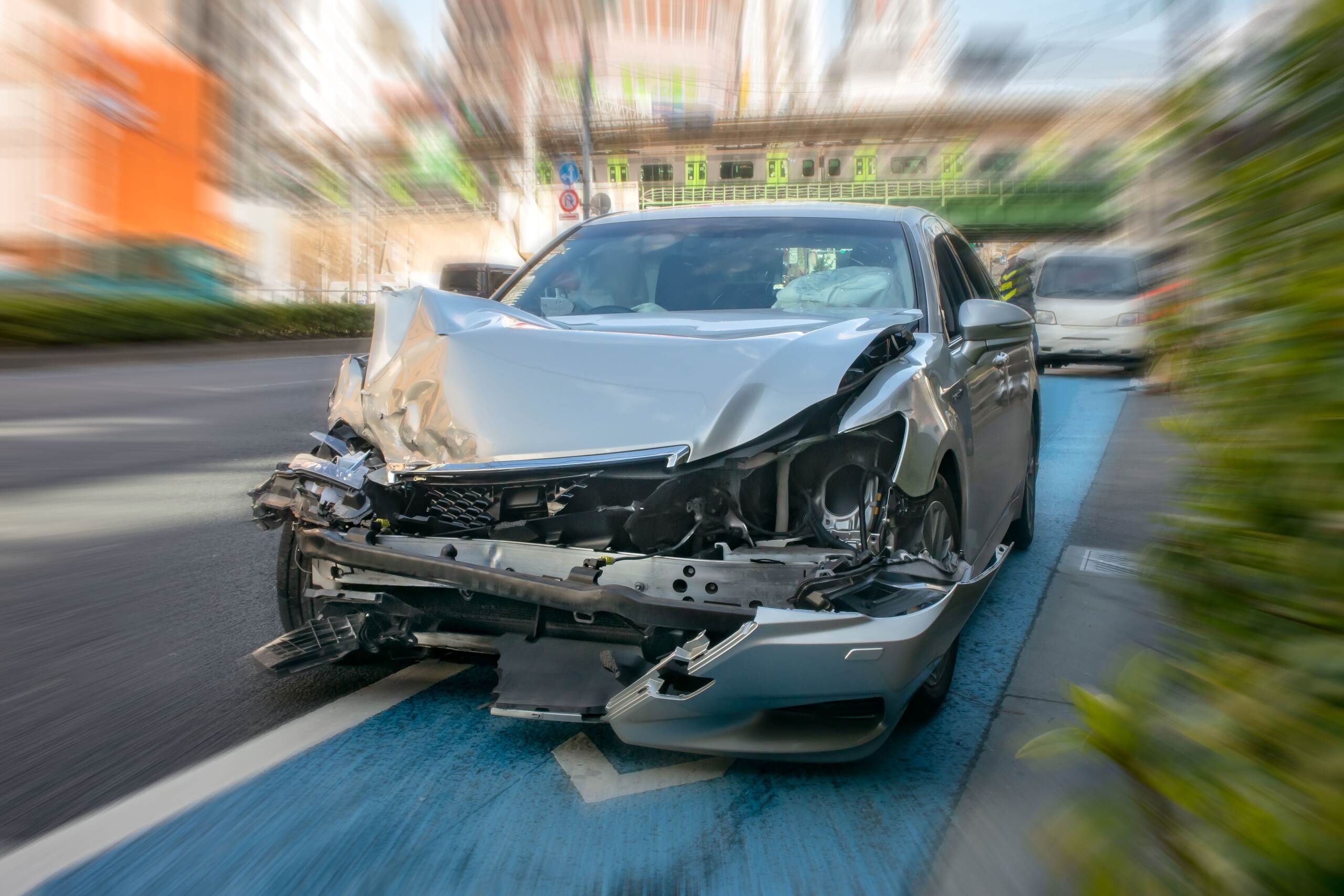 A severely wrecked silver sedan on a city street highlights who pays for my injuries if driver is uninsured in Oklahoma City.