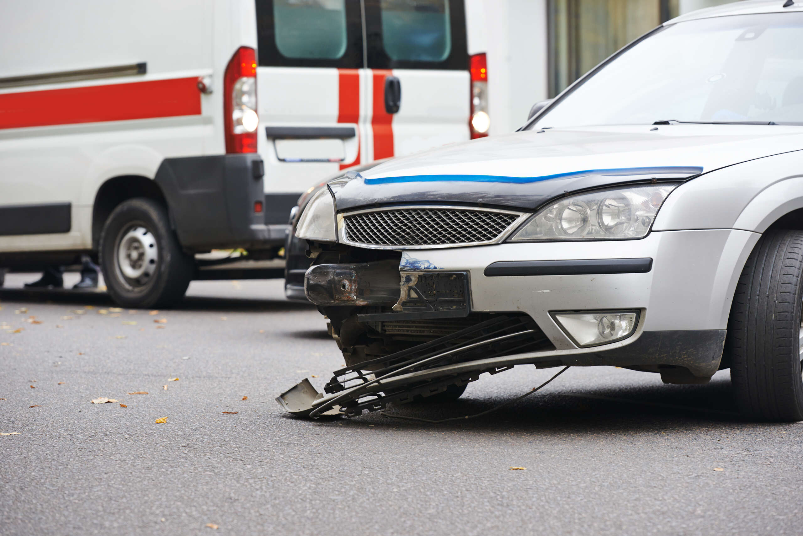 A damaged silver car near an emergency vehicle shows why do I need to hire an OKC hit and run accident attorney OKC crash.